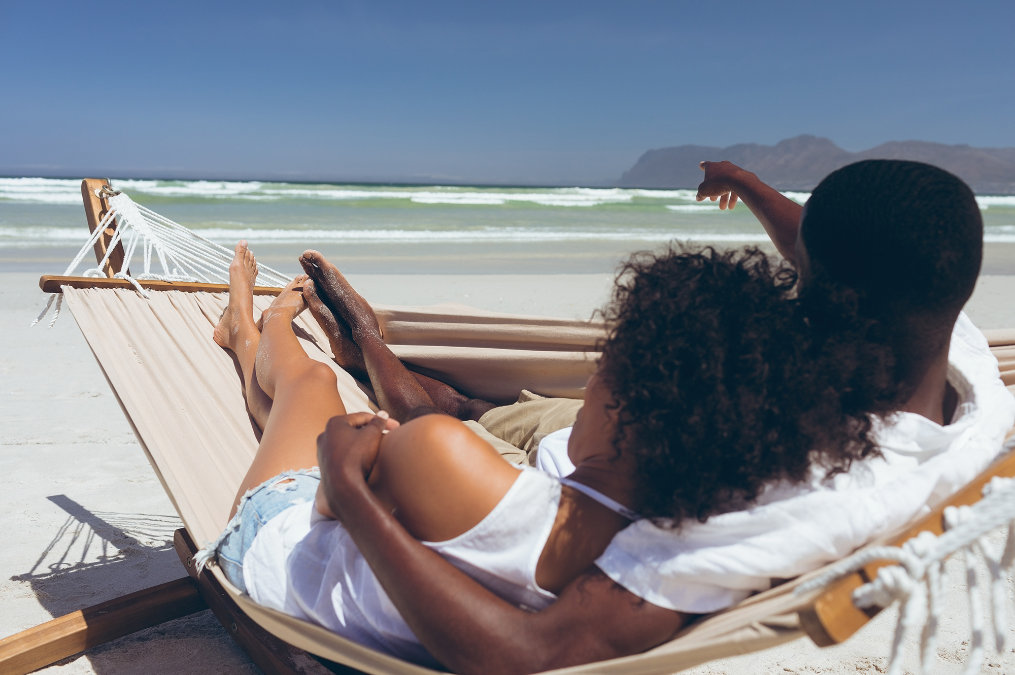 Young couple relaxing on hammock at beach Couple enjoying honeymoon