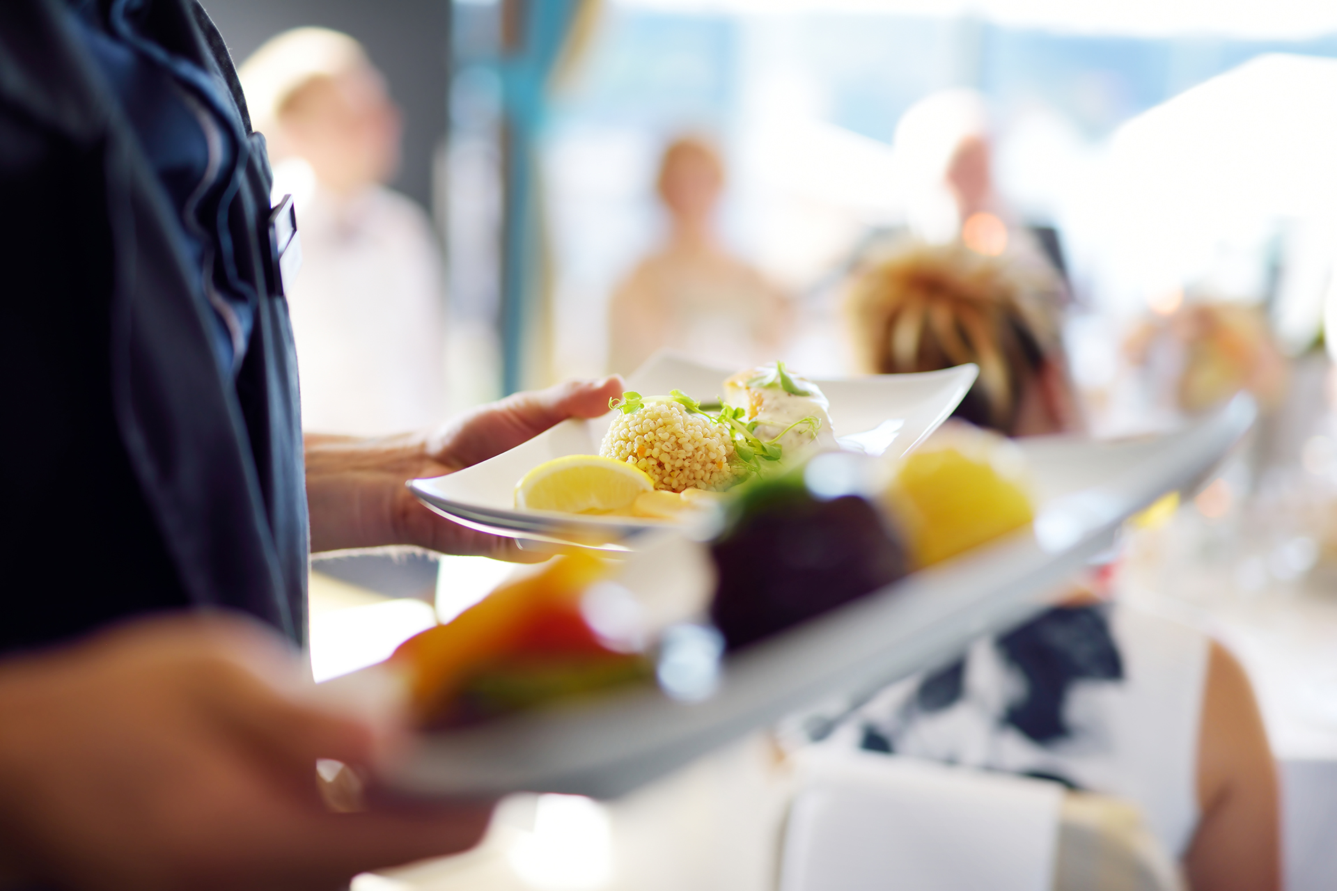 Waiter carrying plates with meat dish on some festive event